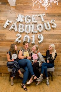 a group of four women posing in front of get fabulous 2019 sign