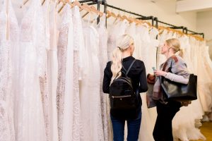 women looking at wedding gowns on a rack at get fabulous event