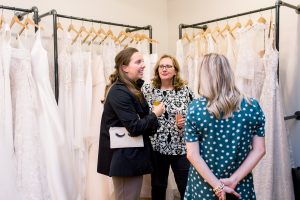 women talking in front of wedding dresses on a rack at get fabulous event