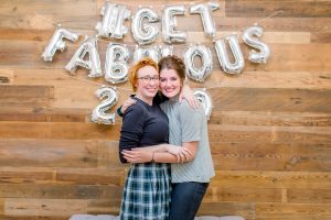 two women hugging in front of get fabulous balloon wall