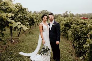 bride in fitted gown in a vineyard with her husband