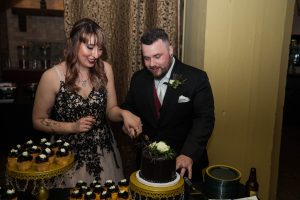 bride and groom cutting black wedding cake