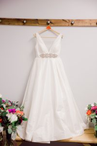 aline wedding dress with a sash hanging on the wall