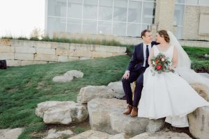 bride and groom sitting on rocks