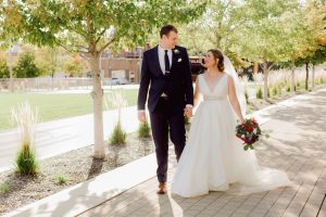 bride and groom walking through a modern sidewalk with trees