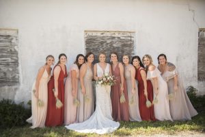 bridal party posing with bride against white wall