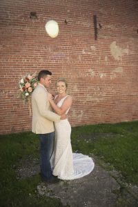 bride and groom hugging in front of brick wall