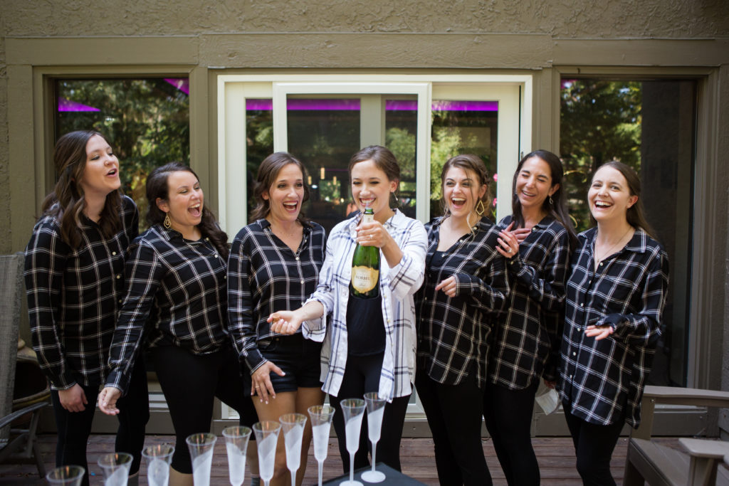 bride and her bridesmaids opening a bottle of champagne