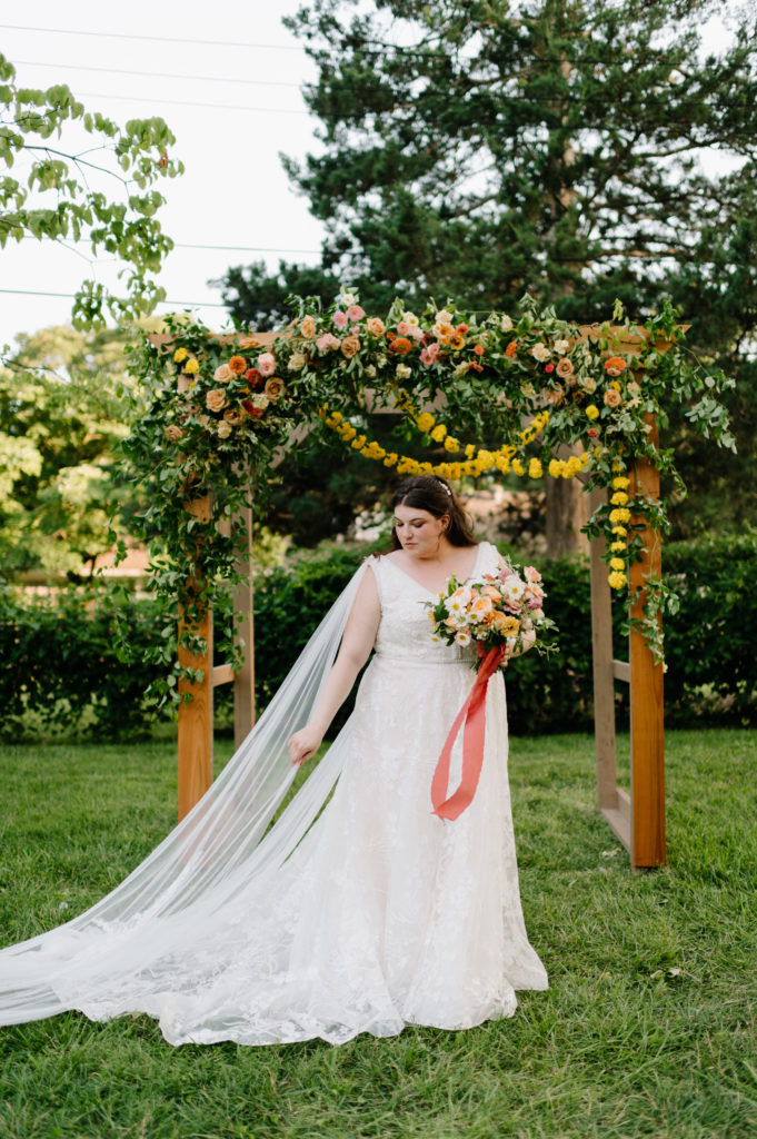 caroline standing in front of the alter in an aline dress and tulle wings from the shoulders