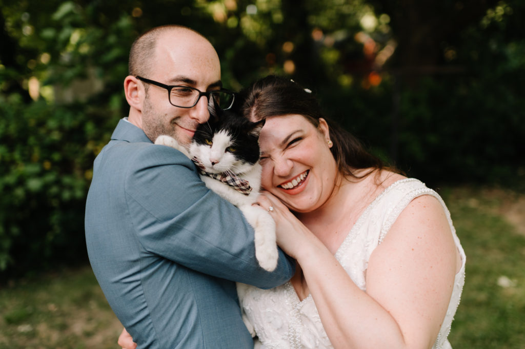 bride and groom holding their cat wearing a bow tie